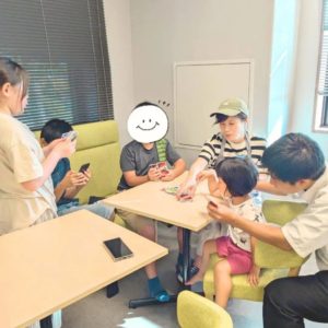 カードゲームをするこどもたちと、女性スタッフの様子
