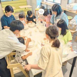 子どもたちが学生ボランティアに教えてもらいながらバズボムを作っている様子