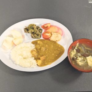 ネオアス村地域食堂で提供された、カレーや桃などが盛り付けられているプレートとお味噌汁の様子