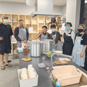 ネオアス村地域食堂のボランティアスタッフたちが笑顔でカメラに向かってポーズをとっている様子