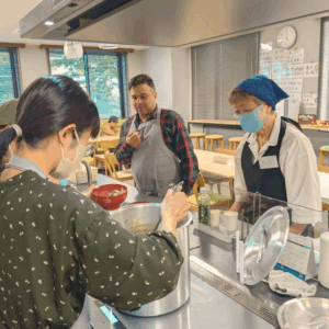 盛り付けや配膳を行う２人の日本人女性ボランティアさんとイラン出身の男性ボランティアさんの様子