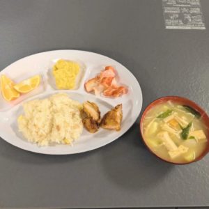 ネオアス村地域食堂で提供された、コーンご飯やからあげなどが盛り付けられたプレートと、お味噌汁の写真