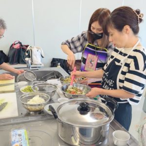 メキシコ出身の女性1人と日本人女性1人がアボカドなどの野菜を刻んでいる様子