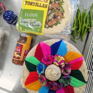 タコスの皮やサルサソースと、カラフルな毛糸で模様がつけられている、タコスを入れておくメキシコのかごの写真