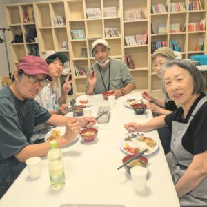 ネオアス村地域食堂で食事をする男性3名と女性2人のスタッフの様子