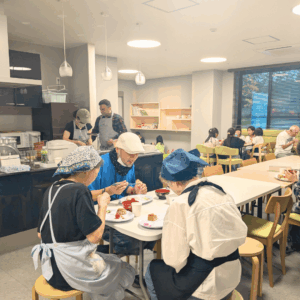 ネオアス村地域食堂で食事や会話を楽しむ利用者さんたちとボランティアスタッフの様子