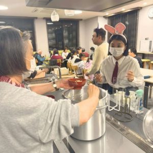 ハロウィンの仮装をして、盛り付けや配膳を行う女性ボランティアと海外出身の男性ボランティアさんと、女性の学生ボランティアの様子