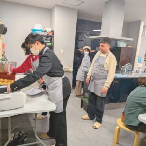 配膳や盛り付けを行う学生ボランティアさんたちと海外出身のボランティアさんの様子