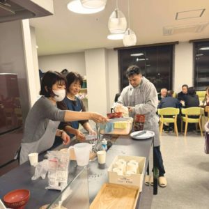 話をしながら食器洗いなどをする2人の女性ボランティアさんと1人の海外出身の男性ボランティアさんの様子