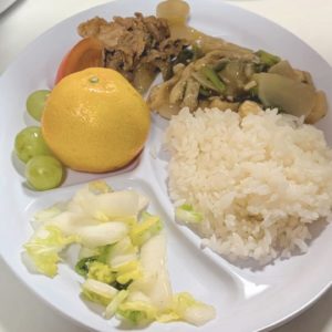 ネオアス村地域食堂で提供された、ご飯や炒め物、みかんなどが載っているプレート