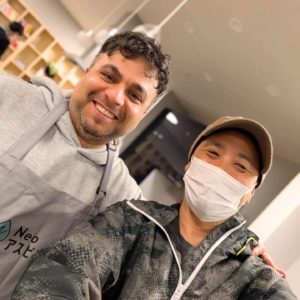 カメラに向かって笑顔を見せるNeoアスビレッジ理事長と海外出身の男性の様子