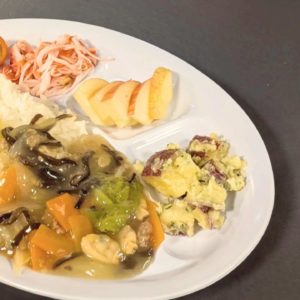 ネオアス村地域食堂で提供された、中華丼やフルーツが盛り付けられたプレート