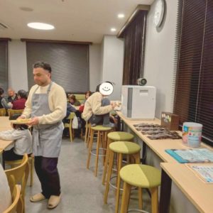 ネオアス村地域食堂で、食事をする子どもたちと、配膳などを行う海外出身のボランティアさんの様子