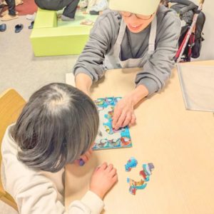 ネオアス村地域食堂に来てくれた子どもと、女性ボランティアが、パズルで遊んでいる様子。