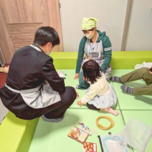 ネオアス村地域食堂のキッズスペースで遊ぶこどもと、見守る学生ボランティアと、スタッフの様子
