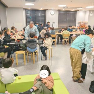 ネオアス村地位食堂で食事や会話を楽しむ参加者さんと、配膳などを行う海外出身のボランティアさんの様子